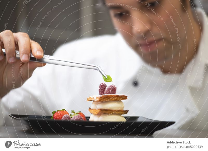 Profikoch serviert Dessert Küchenchef professionell Servieren Speise fokussiert ausgefallen Teller Himbeeren ernst Tisch Mann weiß jung Erwachsener Lebensmittel