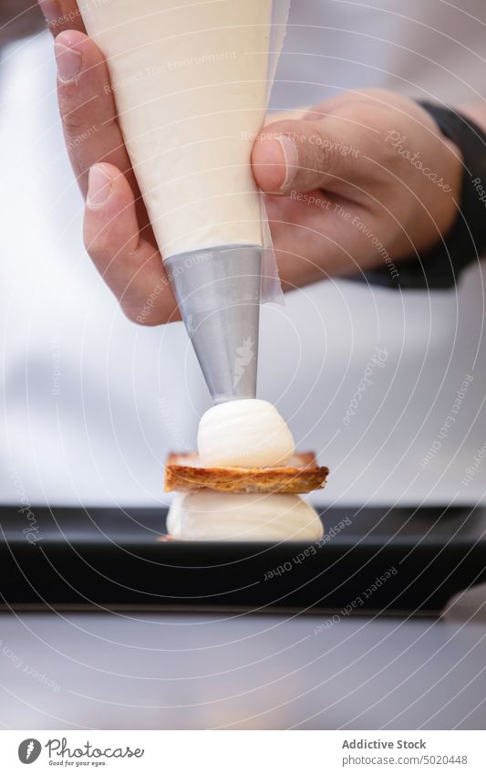 Professioneller Koch bei der Zubereitung eines Desserts mit Beeren und Zuckerguss Küchenchef professionell Spritzbeutel Speise ausgefallen Teller Himbeeren