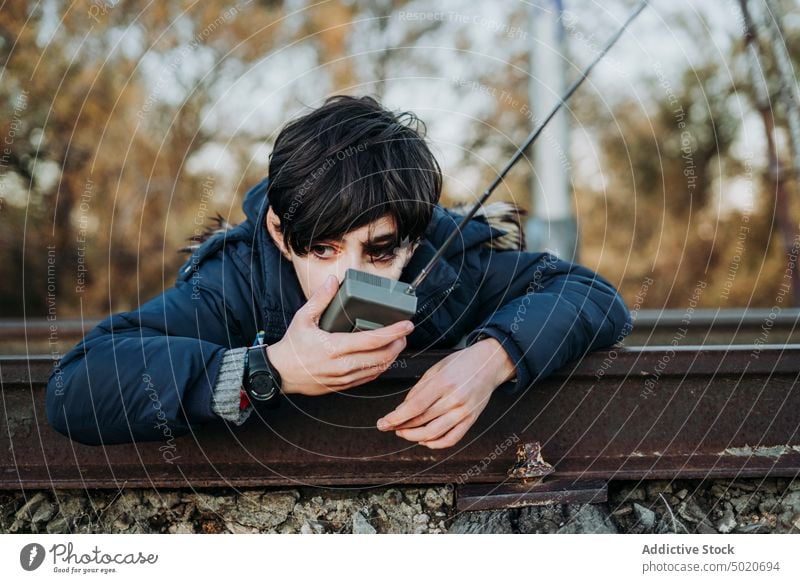 Kleinkind mit Walkie-Talkie auf den Gleisen liegend Junge reden Kind männlich Mitteilung Spielplatz Spielen grün Kinder Porträt blau Radio jung niedlich Spaß