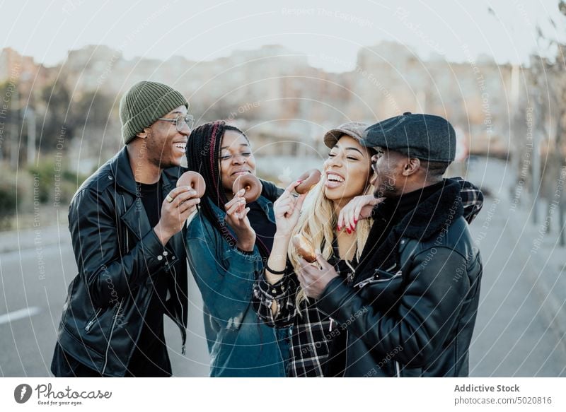 Schwarze Freunde essen Donuts auf der Straße Essen schwarz Großstadt Freizeit Lifestyle Lächeln Zusammensein jung Männer Frauen geschmackvoll lecker Doughnuts