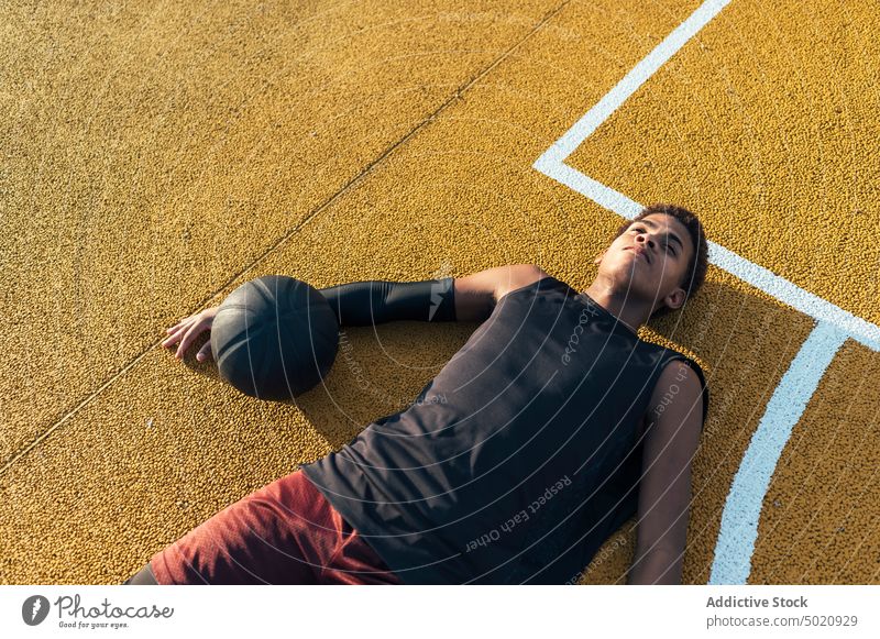 Ruhiger schwarzer Sportler mit Ball auf dem Spielplatz liegend Sitzen Spieler Sportbekleidung müde Ruhe haben Feld männlich kampfstark Athlet Stadion