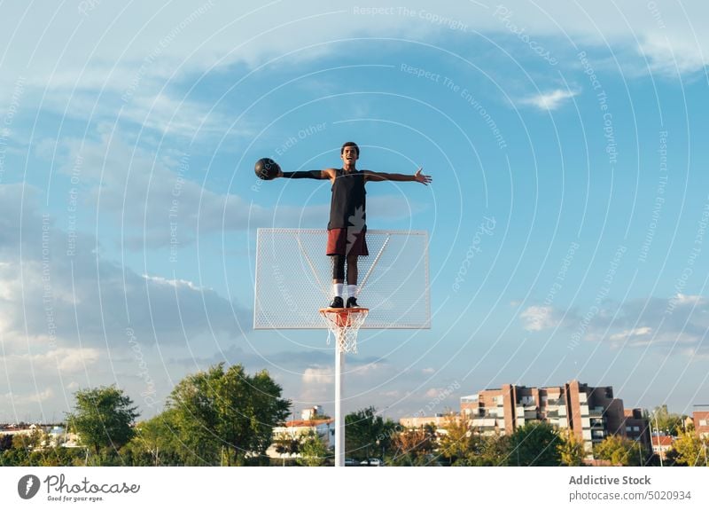 Schwarzer Spieler steht am Basketballkorb und streckt die Arme aus Sportler Reifen strecken Sieg Erfolg professionell Triumph Sportbekleidung Athlet Strategie