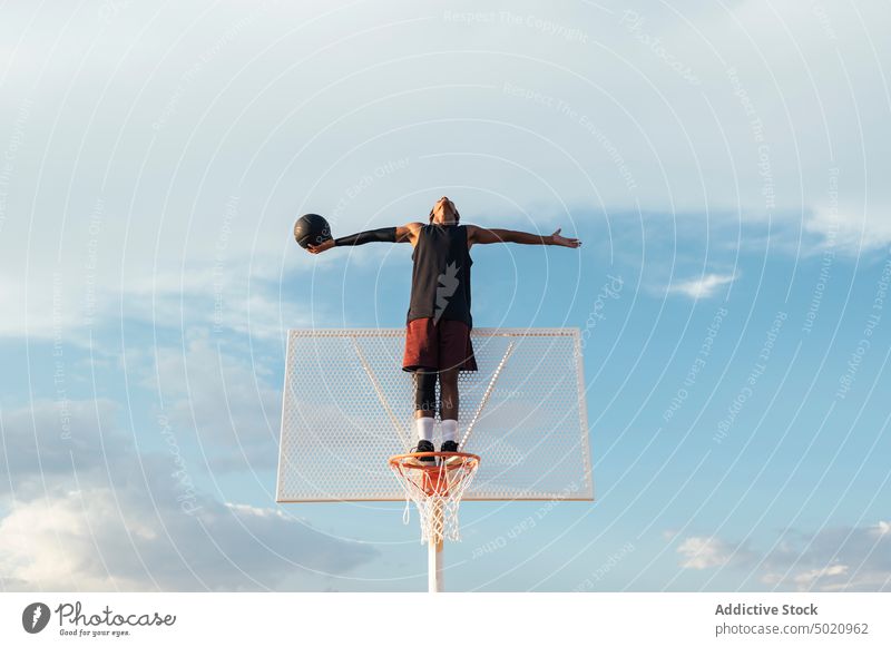 Schwarzer Spieler steht am Basketballkorb und streckt die Arme aus Sportler Reifen strecken Sieg Erfolg professionell Triumph Sportbekleidung Athlet Strategie