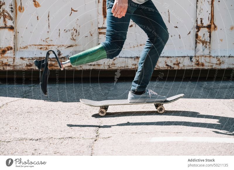 Mann mit Beinprothese fährt Skateboard Mitfahrgelegenheit künstlich Tatkraft Motivation dynamisch Wand Straße Amputierte Großstadt Außenseite jung Beton Energie