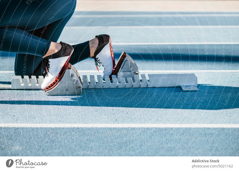 Athlet in Hockstartposition auf Startblöcken Sportlerin Kauerstart Rennen Stadion Rennbahn beginnen Training Fitness Sportbekleidung Übung bereit Konkurrenz