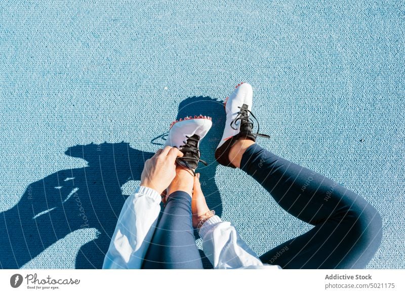 Anonyme Sportlerin beim Anziehen der Laufschuhe während des Trainings angezogen vorbereiten Stadion Rennbahn sitzen Leichtathletik Sportbekleidung Frau Athlet