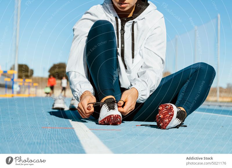 Anonyme Sportlerin beim Anziehen der Laufschuhe während des Trainings angezogen vorbereiten Stadion Rennbahn sitzen Leichtathletik Sportbekleidung Frau Athlet