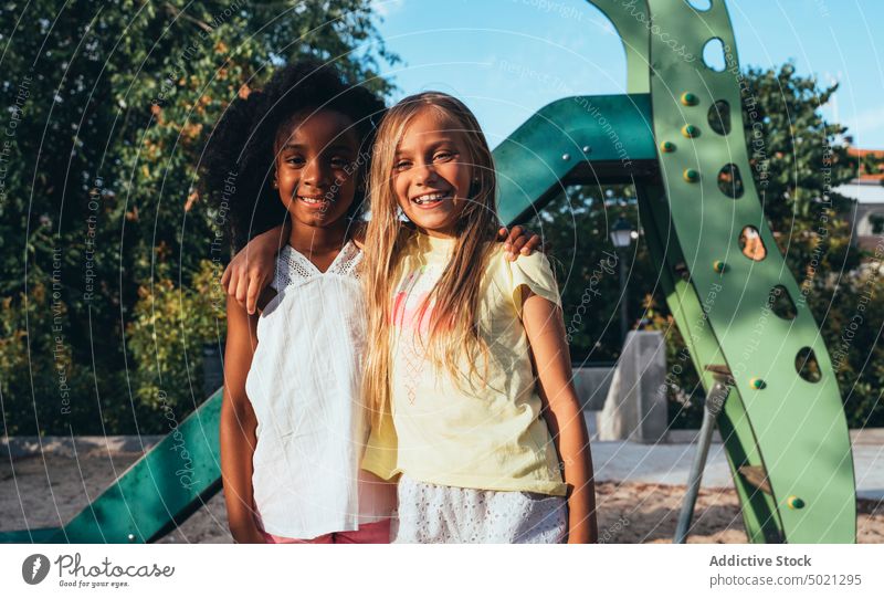 freundliche multiethnische Mädchen stehen und schauen in die Kamera auf einer Rutsche am hellen Tag Spielplatz Sliden Spaß heiter bester Freund rollen Aktivität