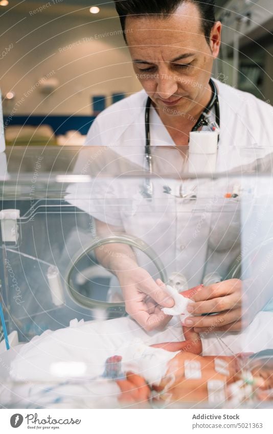 Arzt kümmert sich um neugeborenes Baby im Inkubator Brutkasten medizinisch Kinderärztin Krankenhaus Behandlung Neonatologe Pflege Mann unschuldig