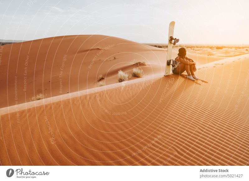 Frau auf Sand sitzend, bereit zum Sandboarding Sport extrem wüst Lifestyle Freizeit Spaß Urlaub reisen Feiertag Tourismus trocknen Düne Genuss vorbereiten