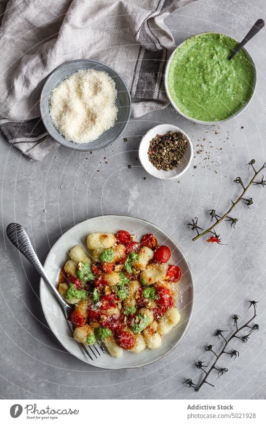 Teller mit leckeren Gnocchi neben Gewürzen Spätzle Speise Tisch Küche Tomate Pesto Käse Paprika Lebensmittel Mahlzeit frisch geschmackvoll Gemüse organisch