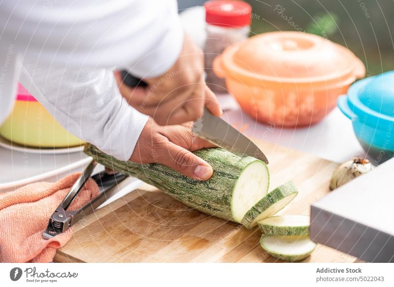 Ein Mann schneidet reife Zucchini mit einem Messer auf einem Schneidebrett geschnitten Koch vorbereiten Küche Lebensmittel Gemüse frisch hacken Scheibe