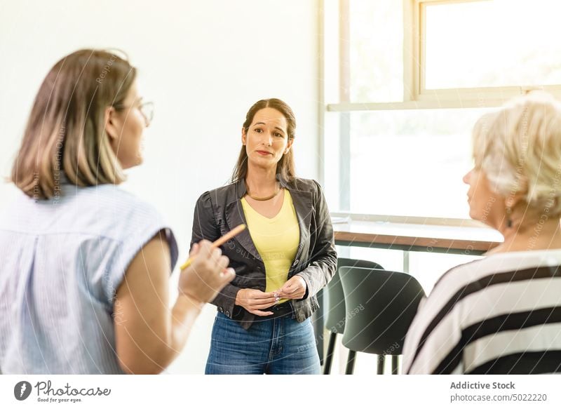 Stehende und sprechende Kollegen auf dem Flur im Büro Frauen Projekt Mitarbeiterin zuhören diskutieren Kommunizieren Arbeitsplatz reden hispanisch ethnisch