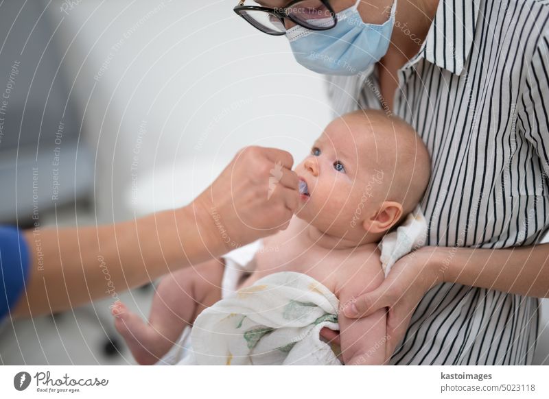 Kinderarzt bei der Verabreichung einer Schluckimpfung gegen die Rotavirus-Infektion an ein kleines Baby im Beisein seiner Mutter. Gesundheitsfürsorge und Krankheitsvorbeugung für Kinder