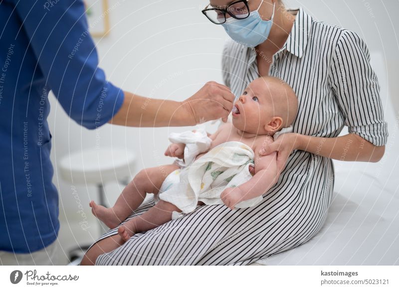 Kinderarzt bei der Verabreichung einer Schluckimpfung gegen die Rotavirus-Infektion an ein kleines Baby im Beisein seiner Mutter. Gesundheitsfürsorge und Krankheitsvorbeugung für Kinder