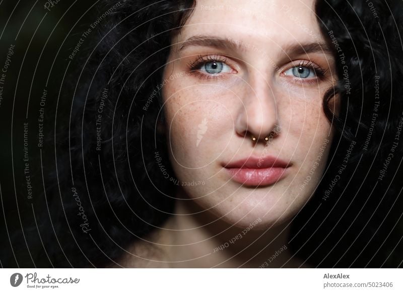 Nahes Portrait einer jungen, dunkelhaarige Frau mit Locken, hellblauen Augen und Sommersprossen junge Frau brünett lange Haare blass schön Haut Gesicht