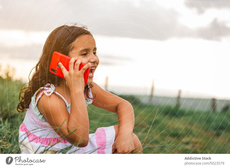 Hispanisches Mädchen, das auf einem Feld mit einem Smartphone spricht sprechen Sonnenuntergang Glück ruhen Wochenende Gras Sommer heiter Freude positiv