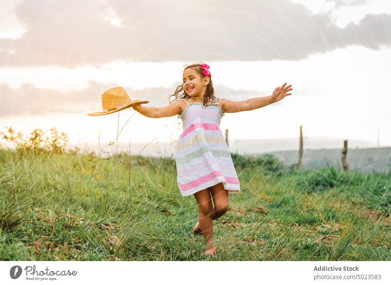 Fröhliches Mädchen im grasbewachsenen Feld Morgen Landschaft Glück Lächeln ruhen Wochenende Sommer Kind Wiese Natur Gras Freude heiter froh Kleid Hut Tastkopf