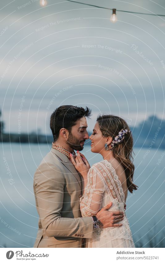 Mann umarmt Braut in der Nähe des Sees bei Nacht Frau Küssen umarmend Valentinsgruß Hochzeit Paar Dame Typ Kleid Anzug geschlossene Augen jung Liebe Heirat