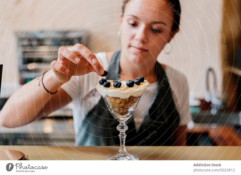 Frau bei der Zubereitung eines Desserts aus Obst und Beeren Kellnerin vorbereitend Frucht Lebensmittel süß Schalen & Schüsseln frisch organisch Blaubeeren