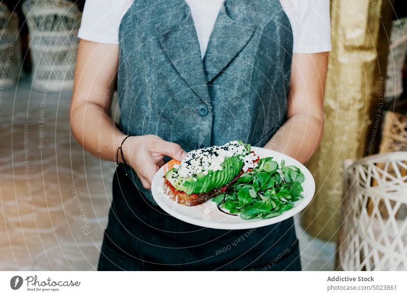 Sandwich mit Avocado und Soße auf einem Teller in den Händen des Kochs Belegtes Brot Mittagessen Zuprosten grün Frühstück Speise Gesundheit frisch Lebensmittel