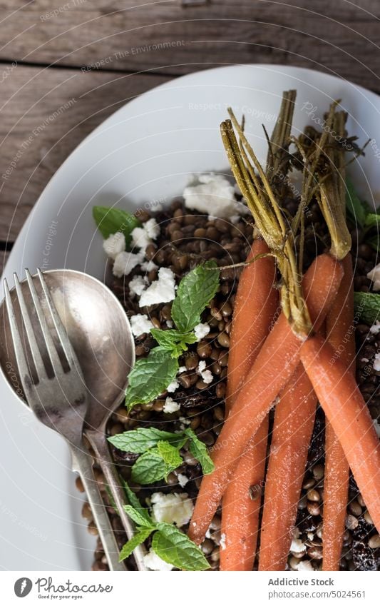 Servierter Salat mit Linsen und Karotten Salatbeilage Möhre serviert lecker Dressing Käse Saucen Hülsenfrüchtler Tisch Essen rustikal Löffel Holzplatte Minze