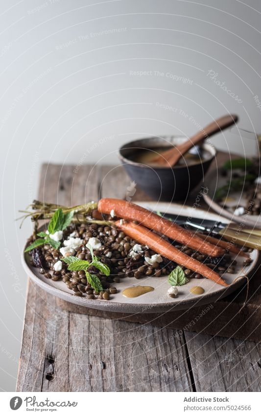 Servierte Teller mit Bio-Salat auf dem Holztisch Platten Salatbeilage Linsen serviert Möhre organisch Dressing grün rustikal Tisch Holzplatte hölzern frisch