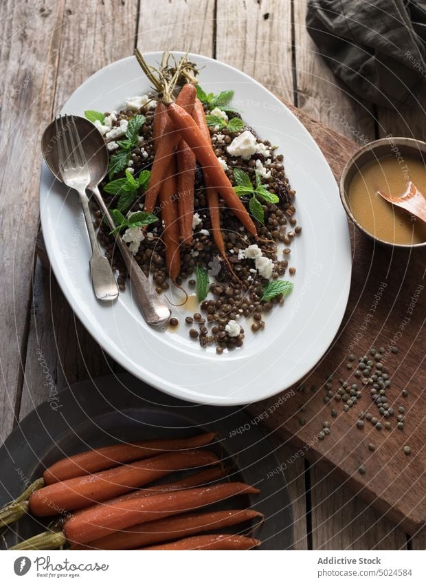 Servierter Salat mit Linsen und Karotten Salatbeilage Möhre serviert lecker Dressing Käse Saucen Hülsenfrüchtler Tisch Essen rustikal Löffel Holzplatte Minze