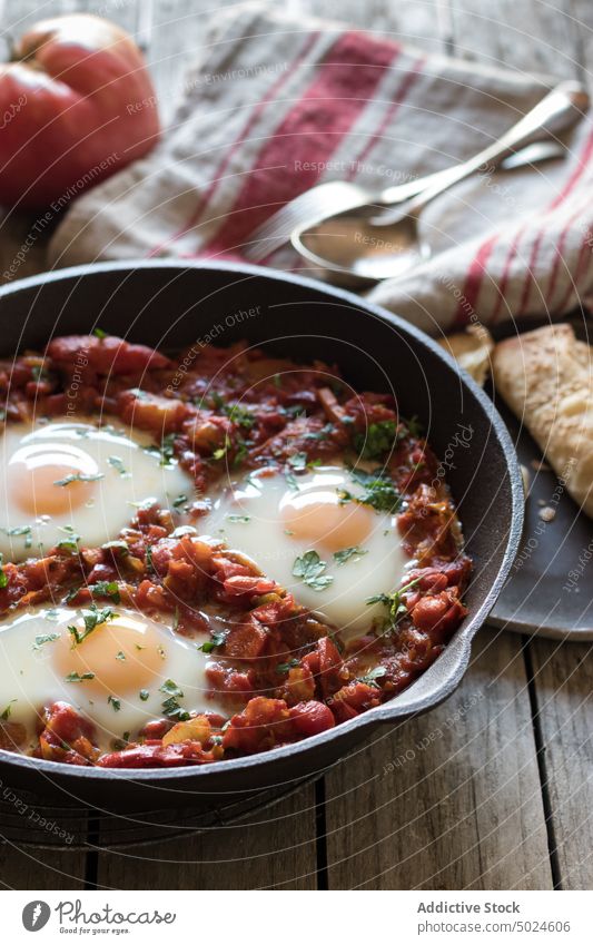 Bratpfanne mit Tomaten und Eiern Pfanne shakshuka serviert lecker Würzig gebraten Saucen rot Holz Frühstück Lebensmittel Speise Petersilie rustikal