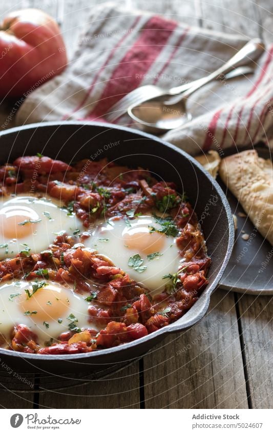 Bratpfanne mit Tomaten und Eiern Pfanne shakshuka serviert lecker Würzig gebraten Saucen rot Holz Frühstück Lebensmittel Speise Petersilie rustikal