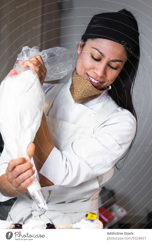 Köchin beim Verzieren von Törtchen mit Schlagsahne Frau Cupcake Bäcker gepeitscht Sahne drücken Backwarenbeutel Bäckerei Veganer Dessert Koch süß Leckerbissen