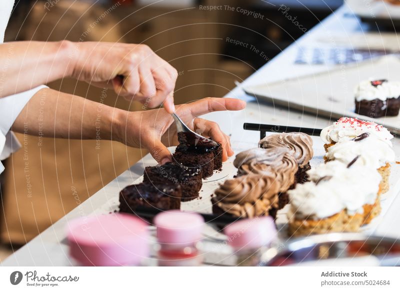 Crop-Koch schmiert Schokolade auf Biskuitkuchen in der Backstube Bäcker Dessert Bäckerei vorbereiten Veganer süß Leckerbissen Kuchen Schliere Schwamm Aufstrich