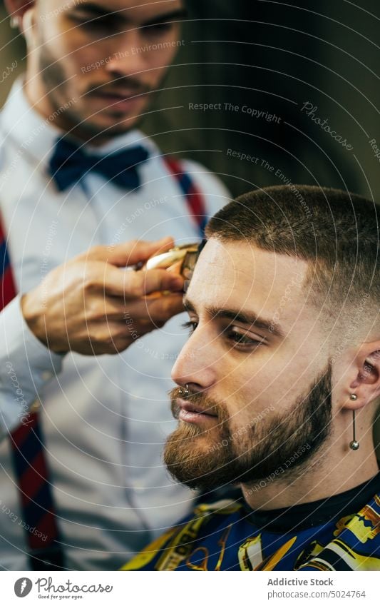 Friseur in einem Friseursalon Vollbart Schönheit Pflege Klient Schermaschine geschnitten elegant Behaarung Haarschnitt Hände Kopf im Innenbereich Lifestyle