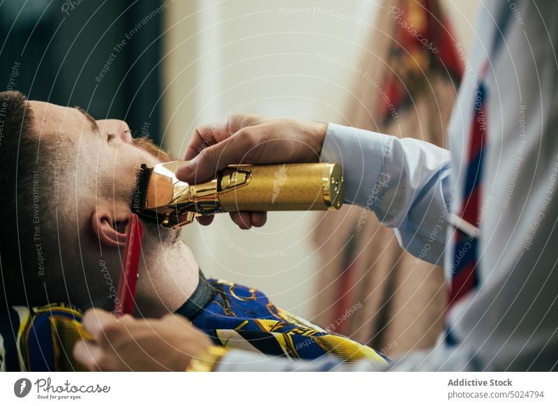 Friseur in einem Friseursalon Vollbart Schönheit Pflege Klient Schermaschine Kamm geschnitten elegant Behaarung Haarschnitt Hände Kopf im Innenbereich Lifestyle