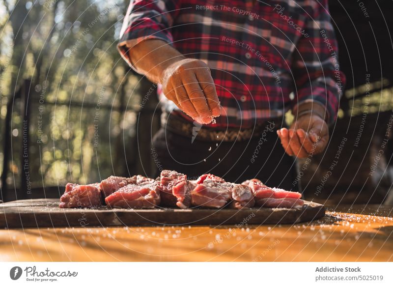 Mann beim Einsalzen von Fleisch für den Grill Lebensmittel setzen vorbereiten Salz lässig Prozess Mahlzeit Koch frisch kulinarisch Bestandteil Küche hölzern