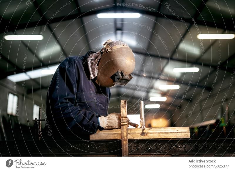 Professioneller Schweißer mit Schutzhelm in der Werkstatt Schweißnaht Metall Mann Maschine dunkel Funken Licht männlich Arbeiter Beruf professionell Werkzeug