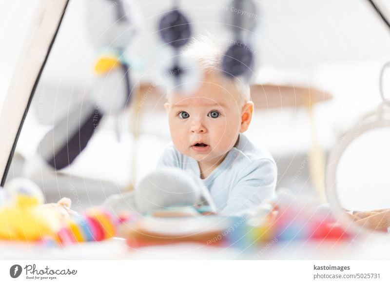 Niedliches Baby spielt mit hängenden Spielzeugen Bogen auf Matte zu Hause Baby-Aktivität und spielen Zentrum für frühe kindliche Entwicklung. Baby spielt zu Hause