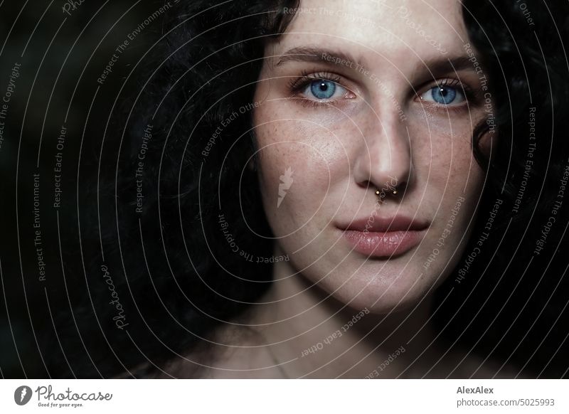 Nahes Portrait einer jungen, dunkelhaarige Frau mit Locken, hellblauen Augen und Sommersprossen junge Frau brünett lange Haare blass schön Haut Gesicht