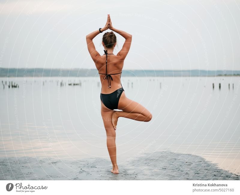 Junge Frau übt Yoga in einer Flussmündung, einem See oder Fluss. Asana, Gleichgewicht. Fitness, Sport. gesunder Lebensstil Konzept. Erwachsener Strand schön