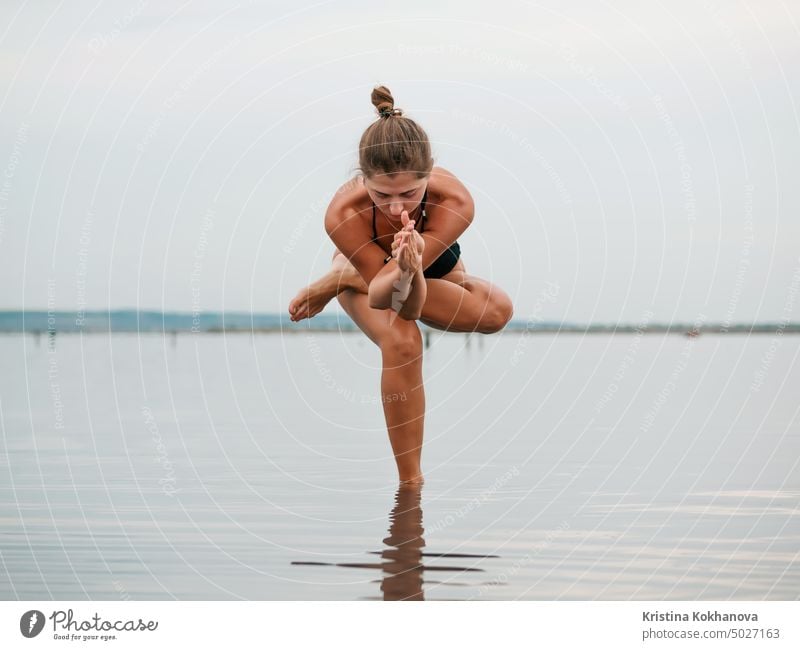 Junge Frau übt Yoga in einer Flussmündung, einem See oder Fluss. Asana, Gleichgewicht. Fitness, Sport. gesunder Lebensstil Konzept. Erwachsener Strand schön