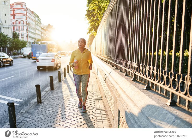 Ältere Sportlerin läuft auf der Straße laufen Sonnenaufgang Herz Fitness Training Straßenbelag Morgen Übung Frau Wellness Wohlbefinden atmen Energie Aktivität