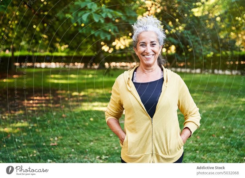 Fröhliche ältere Sportlerin im Park stehend Lächeln Fitness Training Pause Sommer froh Frau Senior gealtert Sportbekleidung positiv Kraft Wohlbefinden Athlet