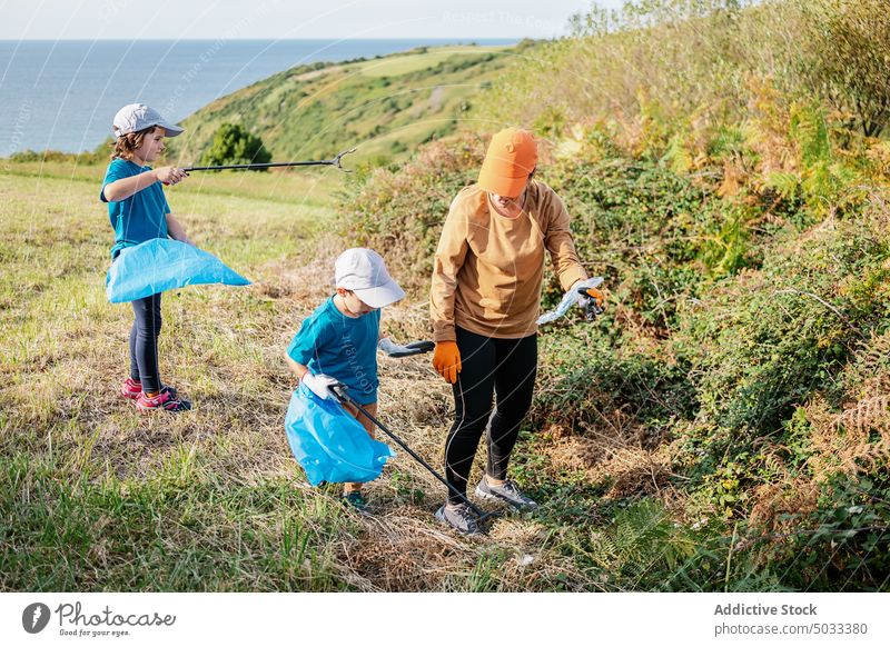 Freiwillige Helfer sammeln Müll auf einer Wiese in der Natur Freiwilliger Umwelt abholen Tasche Frau Kinder Ökologie Landschaft Abfall verschmutzen