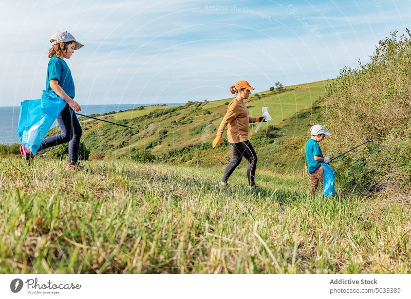 Freiwillige Helfer sammeln Müll auf einer Wiese in der Natur Freiwilliger Umwelt abholen Tasche Frau Kinder Ökologie Landschaft Abfall verschmutzen