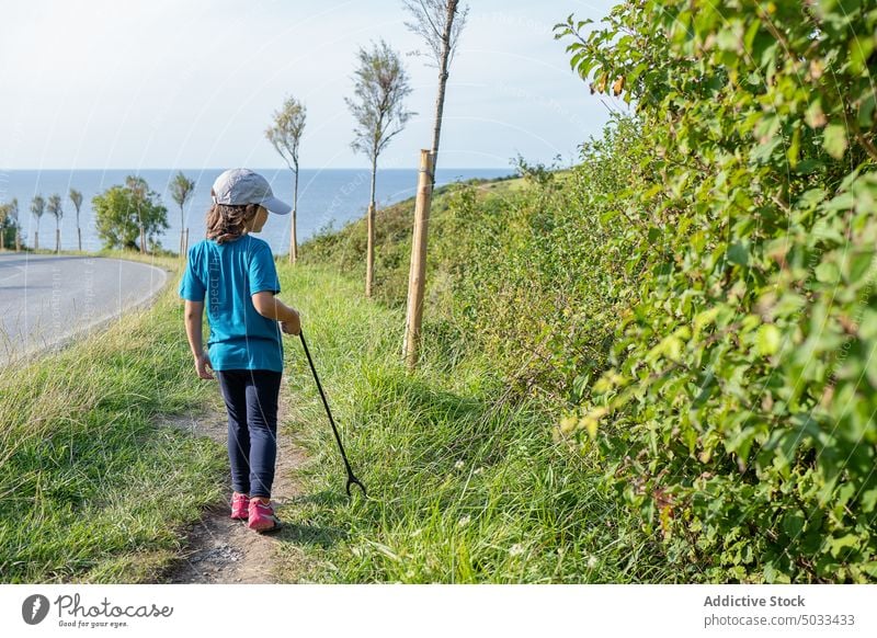 Kind mit Müllzange am grünen Straßenrand stehend Natur Umwelt abholen Freiwilliger MEER Gras Küste Sommer tagsüber Kindheit grasbewachsen außerhalb Ufer Abfall