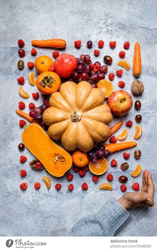 Rohe Kürbisse und gemischtes Herbstgemüse Gemüse Hand fallen sortiert Stillleben Apfel Persimone Ernte frisch Lebensmittel roh Vor dunklem Hintergrund