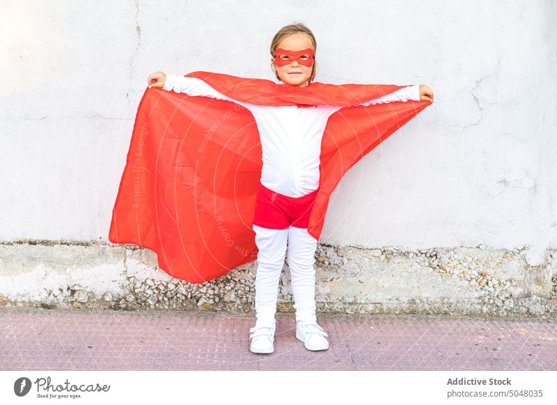 Entzückendes kleines Mädchen im Superhelden-Outfit ausgestreckte Hände Mut selbstbewusst Held Kap wenig niedlich Tracht Kind furchtlos so tun, als ob Kindheit