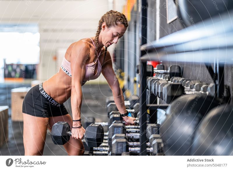 Starke Sportlerin bei Übungen mit Kurzhanteln Athlet heben Training Fitnessstudio stark Gewichtheben Frau Wellness Sportbekleidung Wohlbefinden physisch schwer