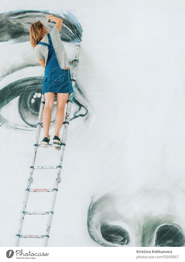 Graffiti-Künstler Zeichnung Gesicht der schönen Frau mit Farbe auf Street Wall. Weibliche Arbeit mit Pinsel. Urban im Freien Kunst Konzept Mann Lifestyle