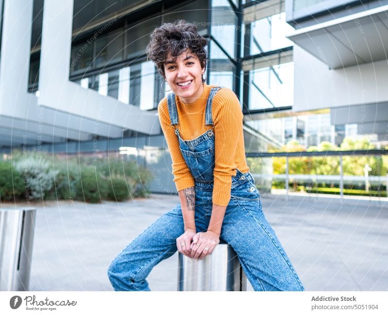 Positive Frau sitzt in der Nähe des Gebäudes Straße heiter Sommer Großstadt genießen Lächeln Stil Kälte Jeanshose sitzen urban positiv brünett gesamt lässig